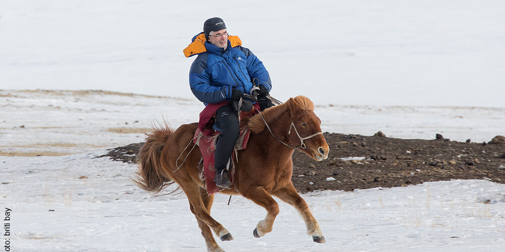 Bernd reitet auf Pferd im Winter in der Mongolei